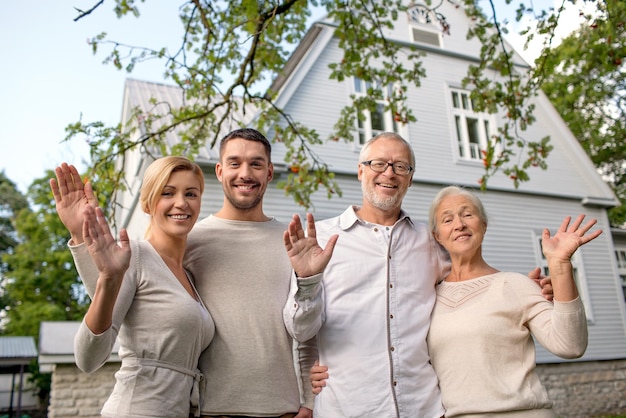 four people standing in front of a house and waving